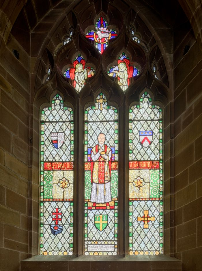Ornate stained glass window depicting religious figures in an English church.